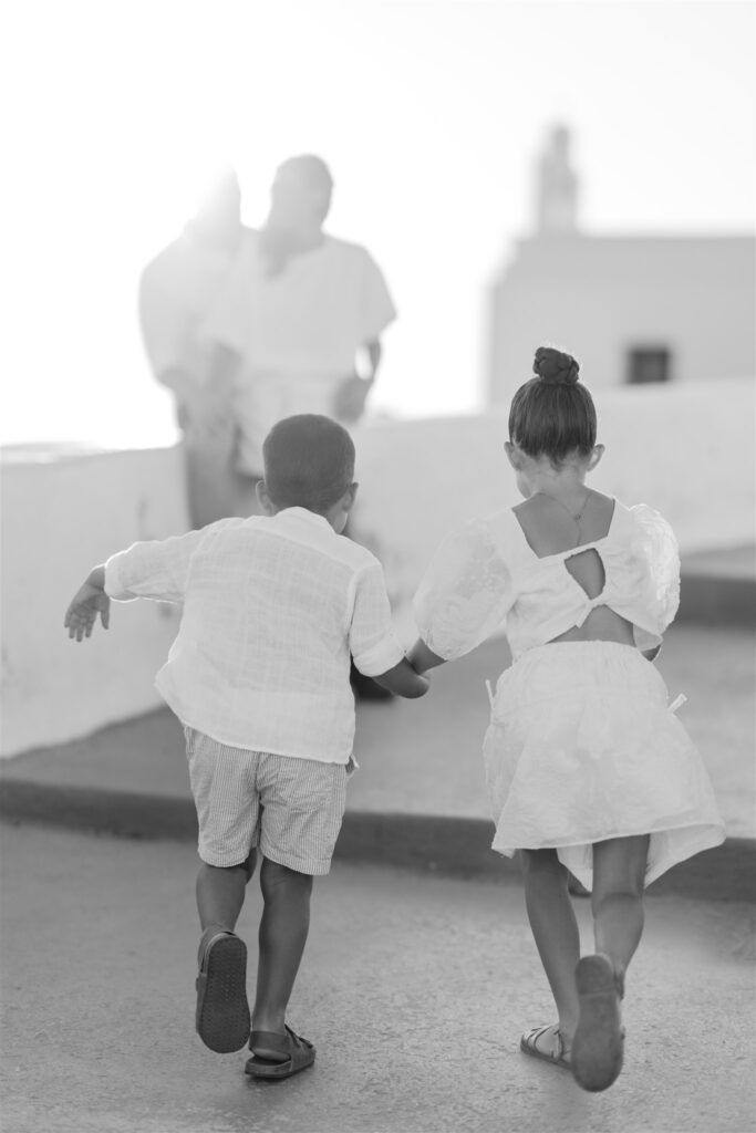 parents watching the children play in santorini at sunset Black and white