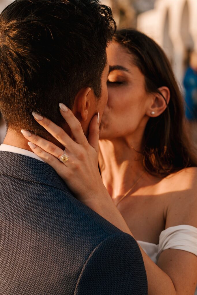 Couple kissing after wedding proposal at sunset in santorini